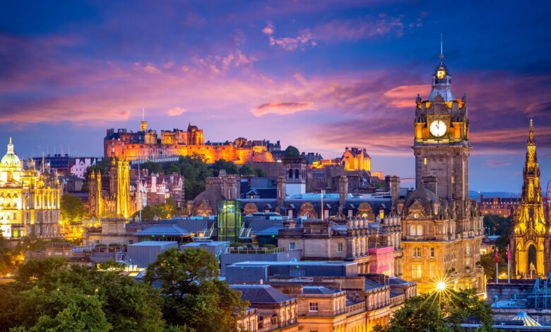 Panoramica di Edimburgo illuminata al tramonto con una torre dell'orologio sul lato destro