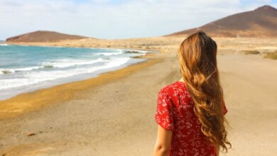 Uma mulher de costas vestida de vermelho em uma praia de Tenerife