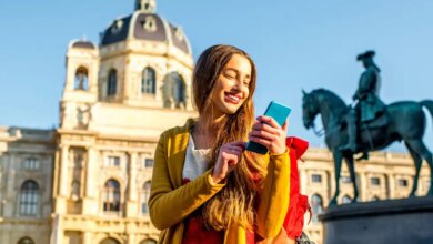 Una donna con il suo cellulare davanti a una scultura equestre e una chiesa con una grande cupola