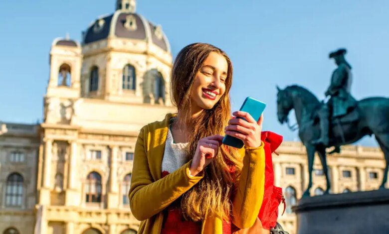 Una donna con il suo cellulare davanti a una scultura equestre e una chiesa con una grande cupola