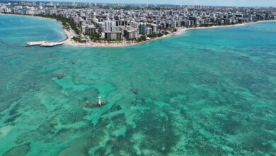 Vista aérea da cidade de Maceió com as águas turquesas e a cidade ao fundo