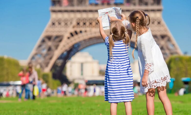 Duas crianças em Paris aproveitando um dia ensolarado em frente à Torre Eiffel